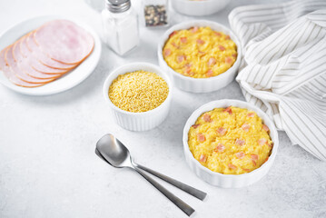 Cheesy millet with ham slices in a baking bowl