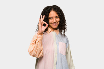 Young african american curly woman isolated cheerful and confident showing ok gesture.