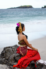 Young woman rests and poses happily on the beach wearing the typical red costume, exotic place.