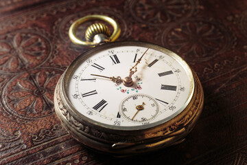 Vintage antique clock on book cover background.