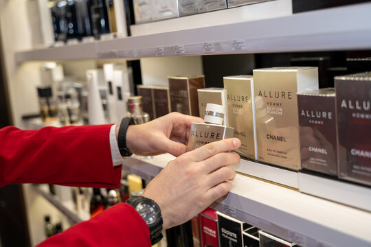 mains d'un homme tenant un parfum allure dans une parfumerie