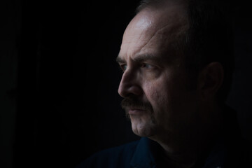 Close-up side portrait of a middle aged man with moustache, being serious