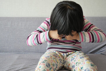 a upset child girl cover her face with hand 