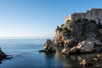 Fototapeta na wymiar Beautiful Lovrinac fortress, on of many prominent Dubrovnik city medieval walls, rising above steep, sharp cliffs and blue Adriatic sea