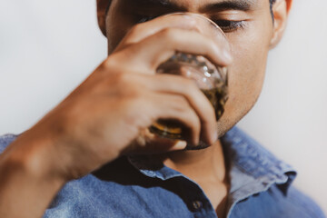 hombre joven triste y mirando con bebida en su mano en un fondo gris y espacio para texto, concepto...