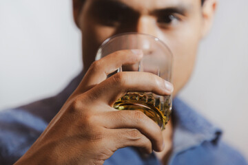 hombre joven triste y mirando con bebida en su mano en un fondo gris y espacio para texto, concepto...