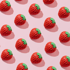Strawberries, creative fruity pattern on a pastel pink background.