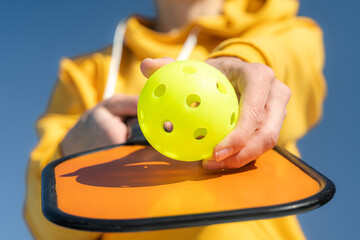 Pickleball paddle and yellow ball close up, woman playing pickleball game, hitting pickleball...