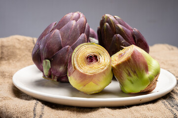 Heads of raw fresh purple romanesco artichoke vegetable heads and pilled hearts