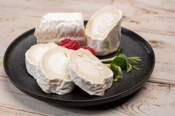 French organic matured white goat cheese with white rind close up served with fresh raspberries