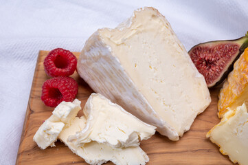Board with french soft cheese Delice de Bourgogne French cow's milk cheese from Burgundy region of France  served with fresh raspberries