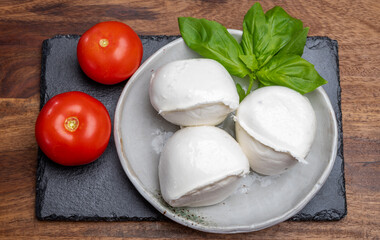 White balls of Italian soft cheese Mozzarella di Bufala Campana served with fresh green basil and red tomato