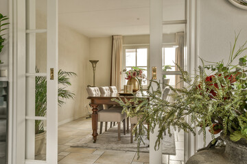 a living room with some plants in the vases on the table and an open door leading to another room