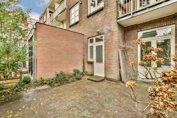 a back yard with plants and flowers in the fore - windowed apartment building, which has been...