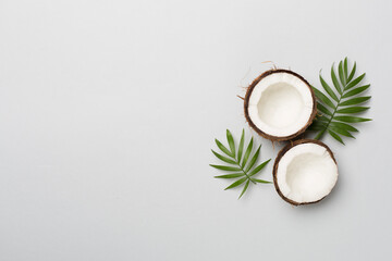 Coconut with leaves on color background, top view