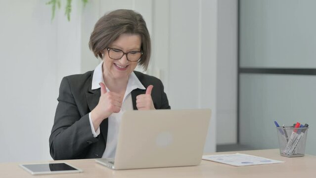Old Businesswoman Celebrating Online Success on Laptop in Office