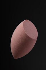 Beauty blender on black background. Brown sponge for cosmetics. Makeup products. Beauty concept. Place for text. Place to copy. Levitation.