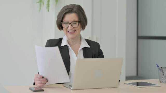 Old Businesswoman Celebrating Success while Doing Paperwork
