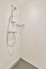 a shower in a white tiled bathroom with grey tile flooring and wall mounted handrails on the walls