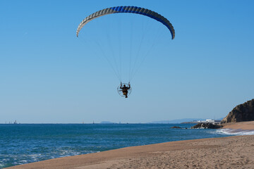 Man in paraglider flying over the beach or sea.