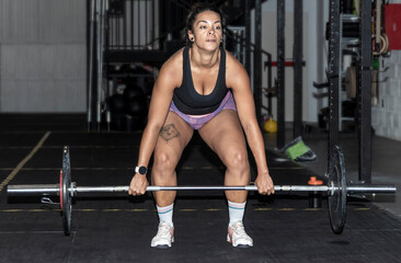 Fototapeta premium Latin woman lifting weight in the gym