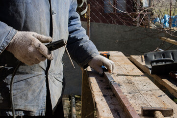 The man makes electric welding at home. Workshop at home. 
The master works in gloves in the village yard
