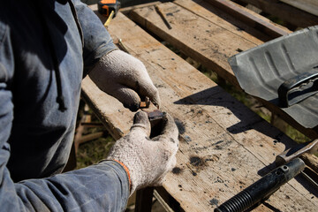 The man makes electric welding at home. Workshop at home. 
The master works in gloves in the village yard
