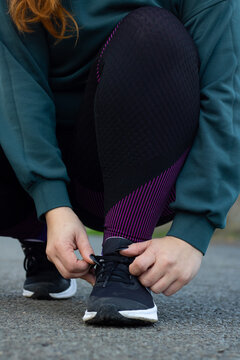 Mujer haciendo deporte agachada amarr&aacute;ndose los cordones de las playeras 