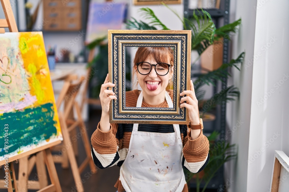 Sticker young beautiful artist woman with face inside empty vintage frame sticking tongue out happy with fun