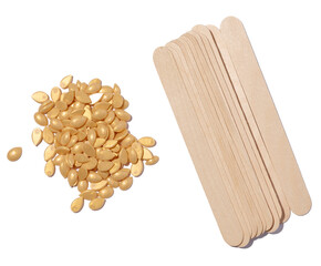 Wooden sticks for applying wax and yellow wax granules for cosmetic procedures on a white isolated...