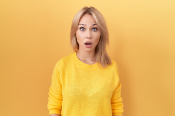 Young caucasian woman wearing yellow sweater afraid and shocked with surprise and amazed expression, fear and excited face.