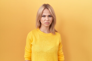 Young caucasian woman wearing yellow sweater skeptic and nervous, frowning upset because of...