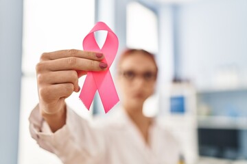 Young caucasian woman scientist holding pink cancer ribbon at laboratory
