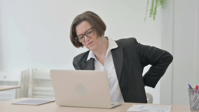 Old Businesswoman having Back Pain while using Laptop