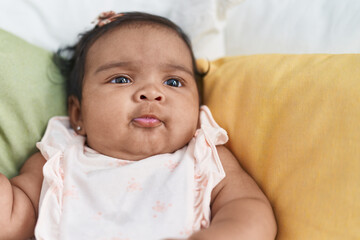 African american baby sitting on bed with relaxed expression at bedroom