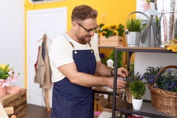 Middle age man florist smiling confident touching lavender plant at flower shop