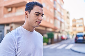 Young hispanic man looking to the side with serious expression at street