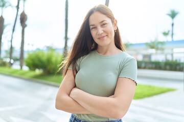 Young beautiful woman standing with arms crossed gesture at street