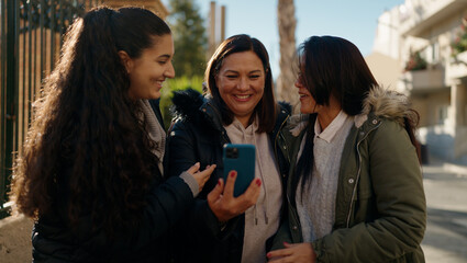 Mother and daugthers using smartphone standing together at street