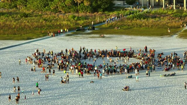 Aerial view of large crowd of people dancing and having fun on sandy beach at sea shore during summer vacations. Outdoor activities during traveling time