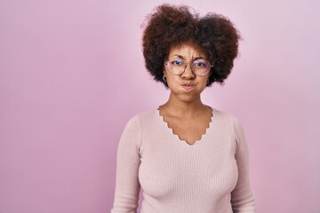 Young african american woman standing over pink background puffing cheeks with funny face. mouth inflated with air, crazy expression.