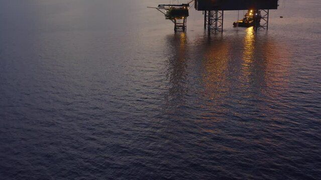 Jack up drilling rig and production platform in the middle of the ocean at sunrise time
