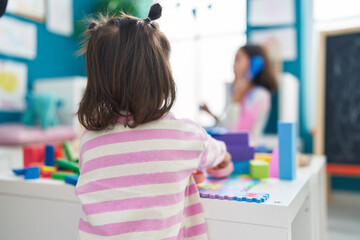 Adorable chinese toddler playing with toys standing at kindergarten