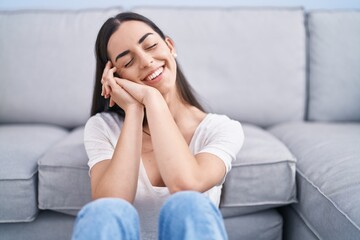 Young hispanic woman smiling confident sitting on floor at home