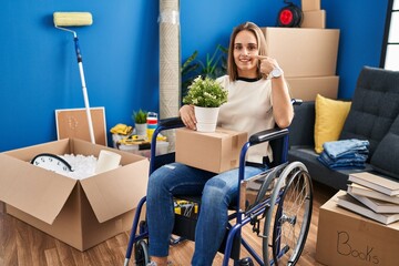 Young woman sitting on wheelchair moving to a new home pointing with hand finger to face and nose, smiling cheerful. beauty concept