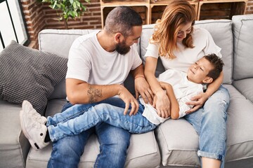 Family doing tickle to son sitting on sofa at home