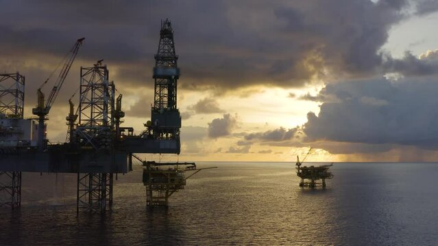 Jack up drilling rig and production platform in the middle of the ocean at sunrise time

