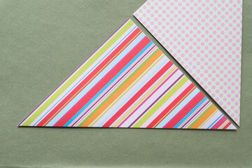 two folded scrapbook paper triangles on rough green paper