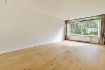 an empty living room with wood flooring and large window looking out onto the trees in the garden behind it