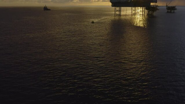 Jack up drilling rig and production platform in the middle of the ocean at sunrise time
